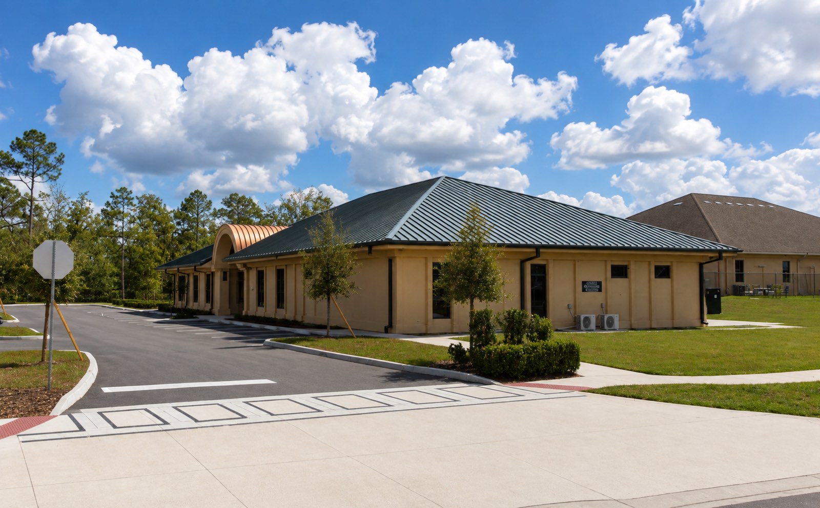 Commonwealth 991 in Sun City Center: a single-story office building with a dark green standing-seam metal roof and a copper barrel vault over the entrance.