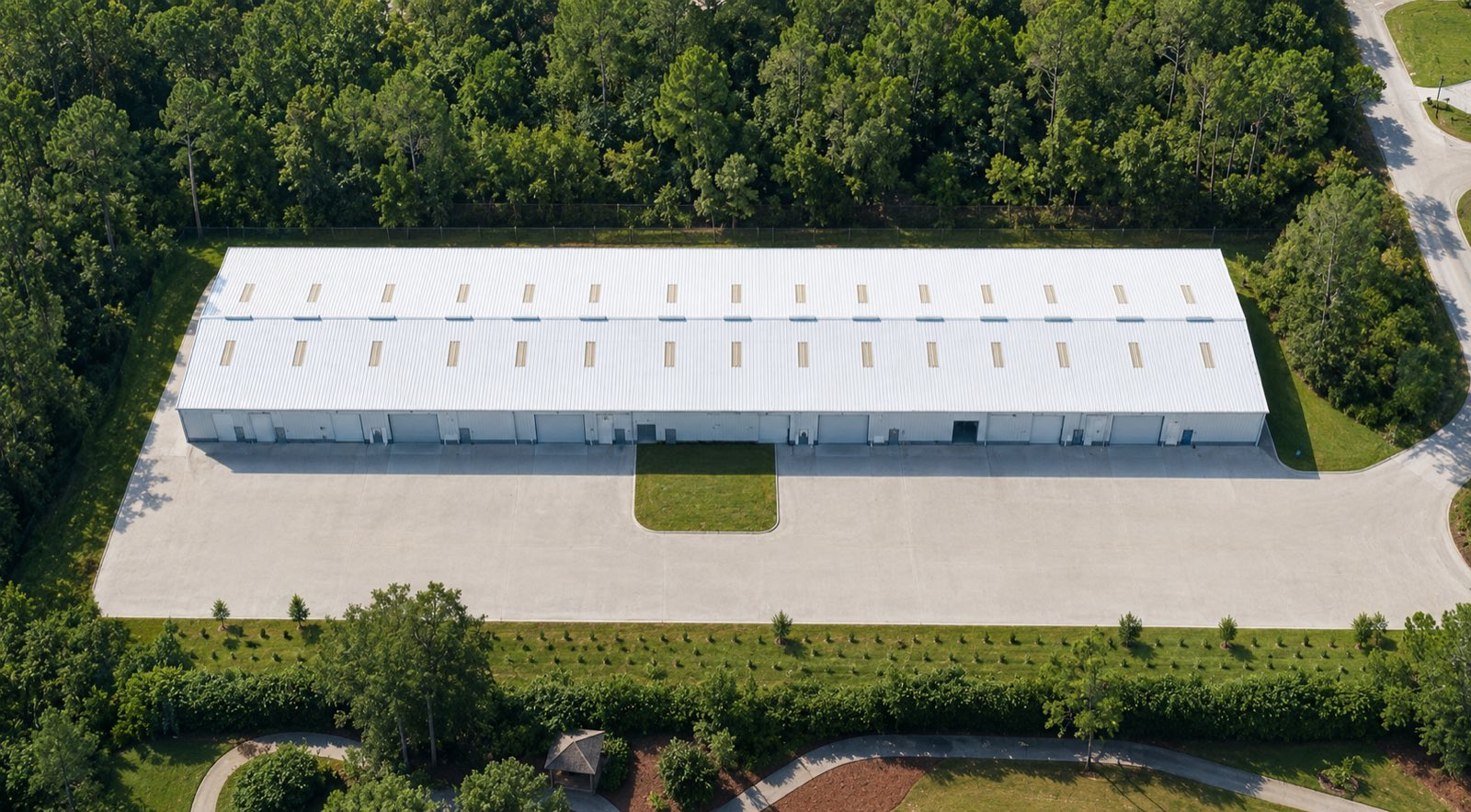 Aerial view of the Crystal Prime Warehouse, a long white metal building with roll-up doors along its length and a deep concrete truck apron.